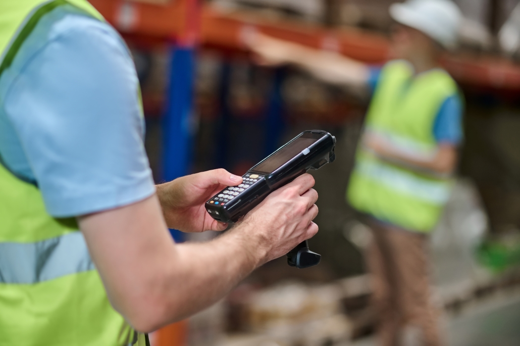 Male hands holding barcode scanner at industrial warehouse